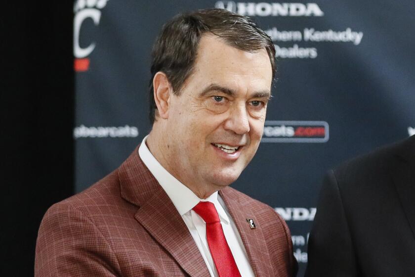 John Brannen, center, poses for a picture with athletic director Michael Robert Bohn, left, and university president Neville Pinto, right, during a news conference to formally announce Brannen's hiring as Cincinnati's men's basketball coach after leading Northern Kentucky to two NCAA Tournament appearances in the last three years, Monday, April 15, 2019, in Cincinnati. Brannen replaces Mick Cronin, who left Cincinnati for the UCLA job. (AP Photo/John Minchillo)