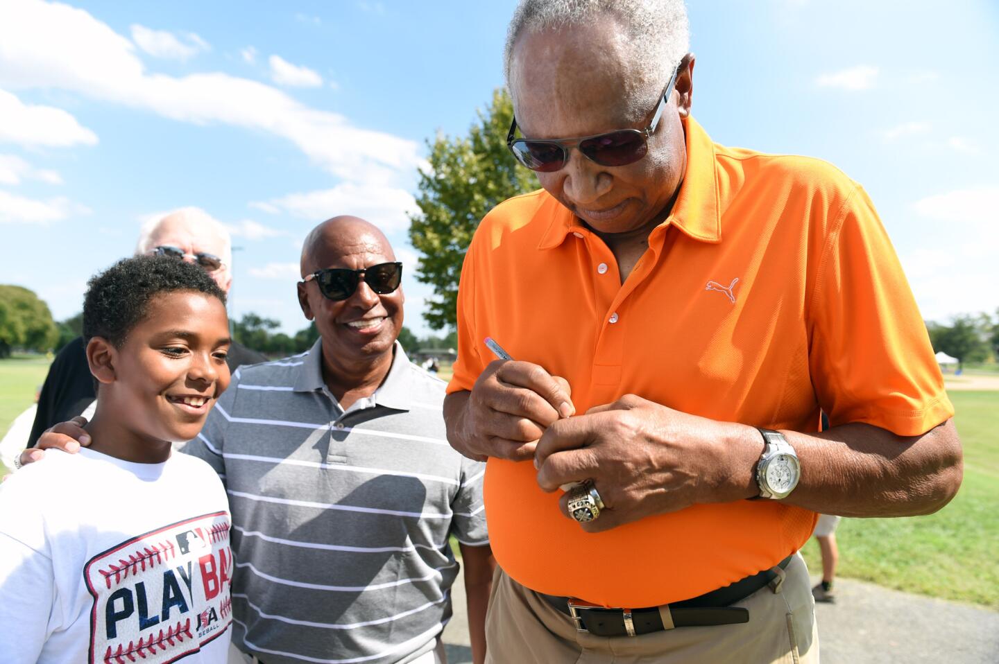 Baltimore, Md.--8/26/15-- Major league Hall of Famer and former Orioles star Frank Robinson, right, autographs a baseball for Jean Zayas, 13, left, during the Play Ball event at Carroll Park on Aug. 26, 2015.