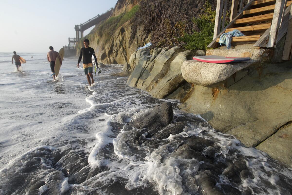 High-tide waters hit the base of the bluffs at Grandview beach in north Encinitas Thursday.
