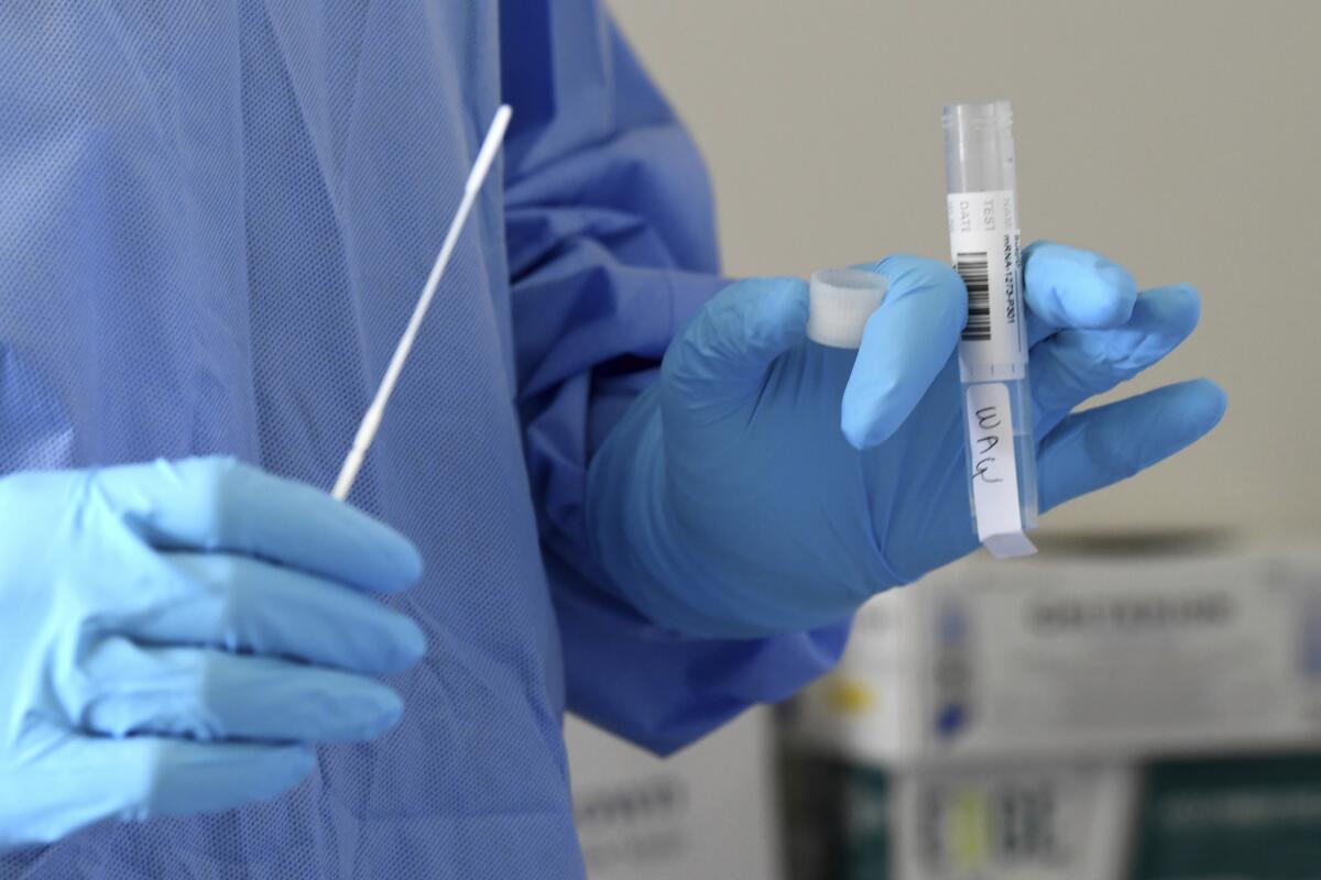 A gloved University of Miami nurse prepares to test a volunteer for COVID-19.