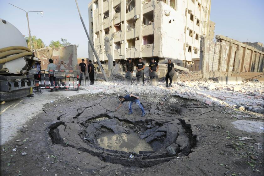 An Egyptian worker checks a hole in the street after a bombing in Cairo that wounded dozens. Islamic State claimed responsibility.