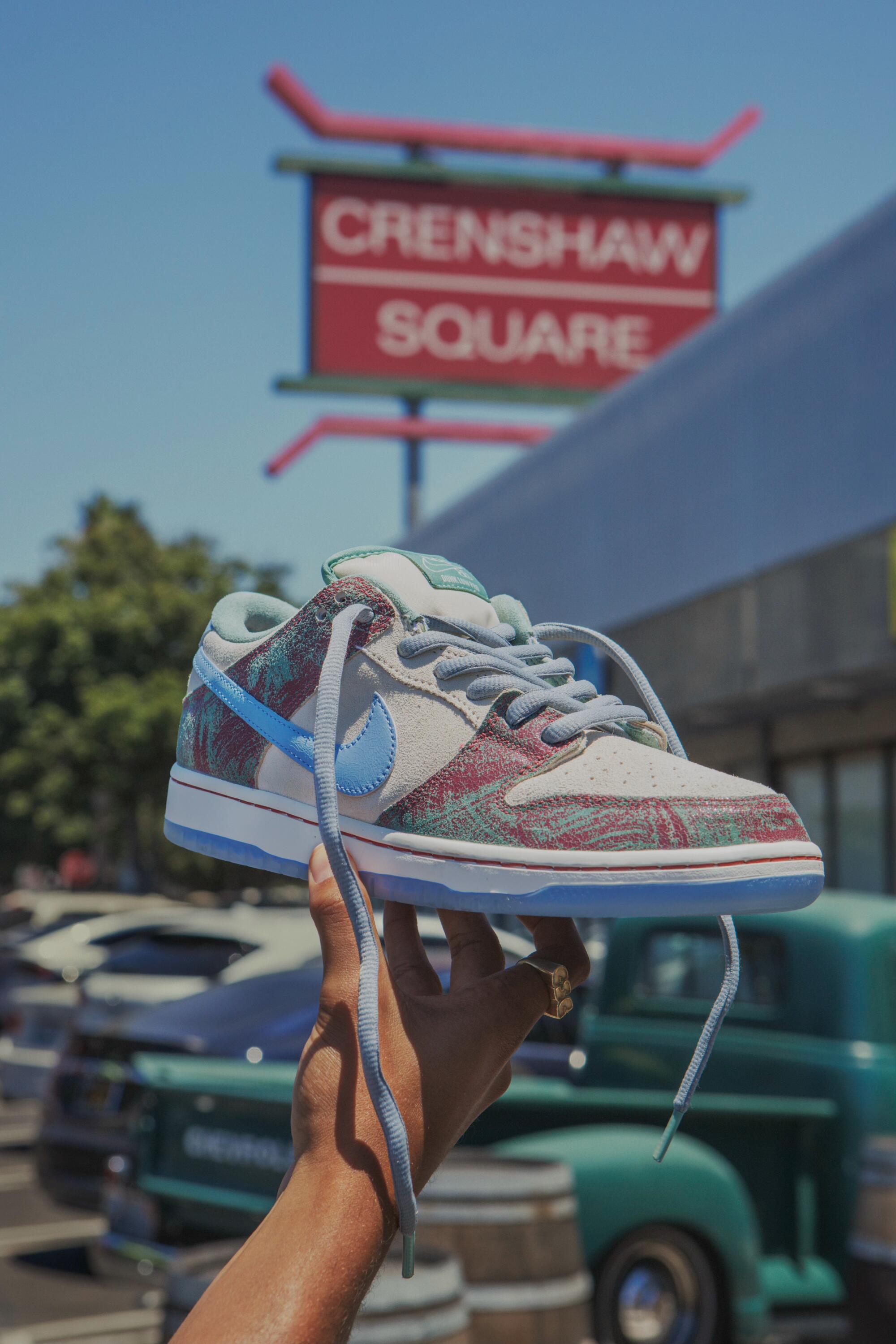 a hand holds up a Crenshaw Skate Club x Nike sneaker with translucent outsoles and cartoon illustrations