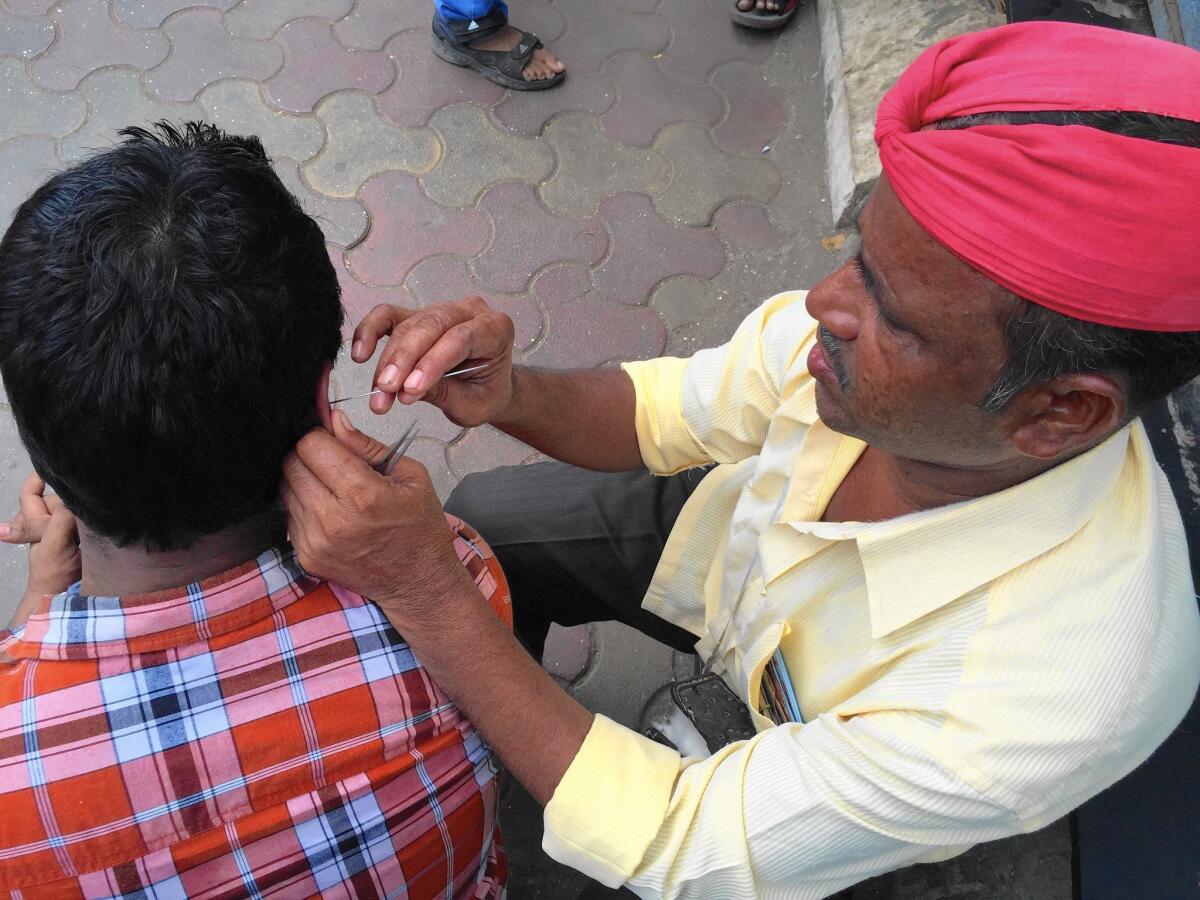 Sayed Mehboob, a professional ear cleaner, works on a customer on a street in Mumbai, India.