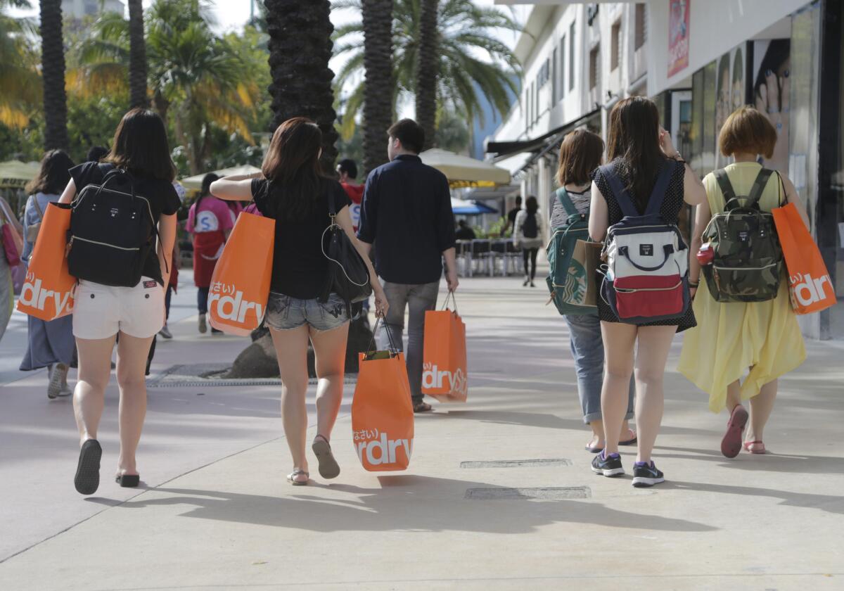 Tourists from Taiwan carry shopping bags as they walk along Lincoln Road Mall, a pedestrian area featuring retail shops and restaurants, in Miami Beach, Fla., on Feb. 3.