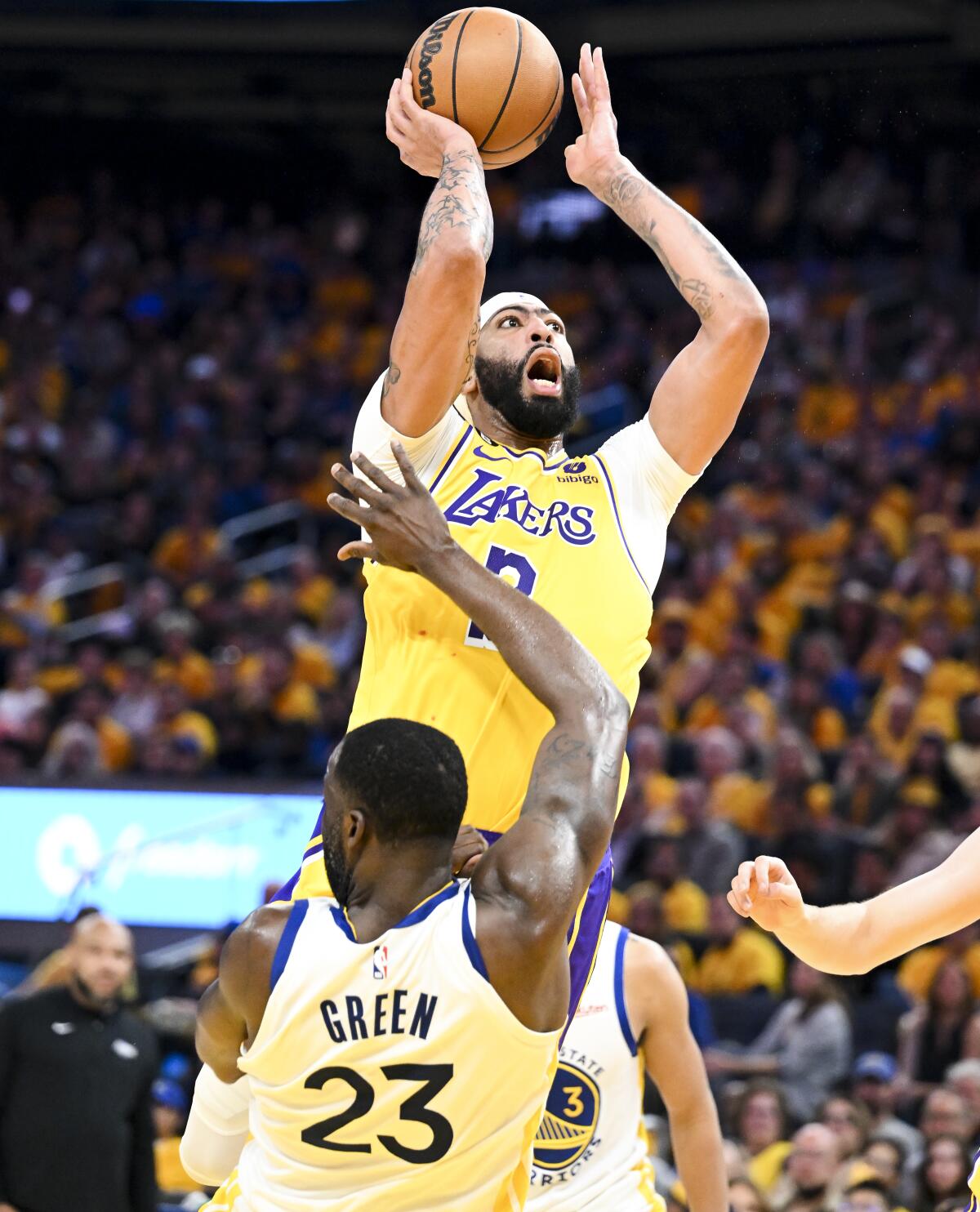 Warriors forward Draymond Green, front, draws an offensive foul against Lakers forward Anthony Davis on a shot attempt.