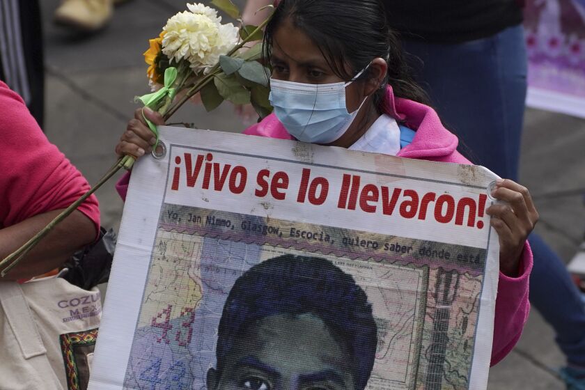 Un familiar de uno de los 43 estudiantes universitarios de Ayotzinapa desaparecidos marcha con un cartel que tiene la imagen de su ser querido y la frase "¡Vivo se lo llevaron!", en la Ciudad de México, el lunes 26 de septiembre de 2022, al cumplirse un nuevo aniversario de la desaparición de los estudiantes en Iguala, Guerrero, en 2014. (Foto AP/Marco Ugarte)