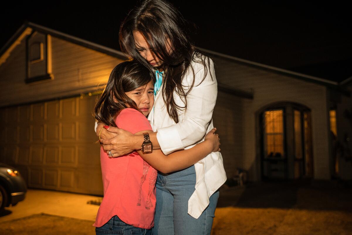 Hmong community advocate Paula Yang hugs Dayvina Xiong, 6, niece of shooting victim, Kou Xiong. Family members gathered for the candlelight vigil for four men who were shot killed in the backyard of this residence on Sunday, during a family party while watching a football game.