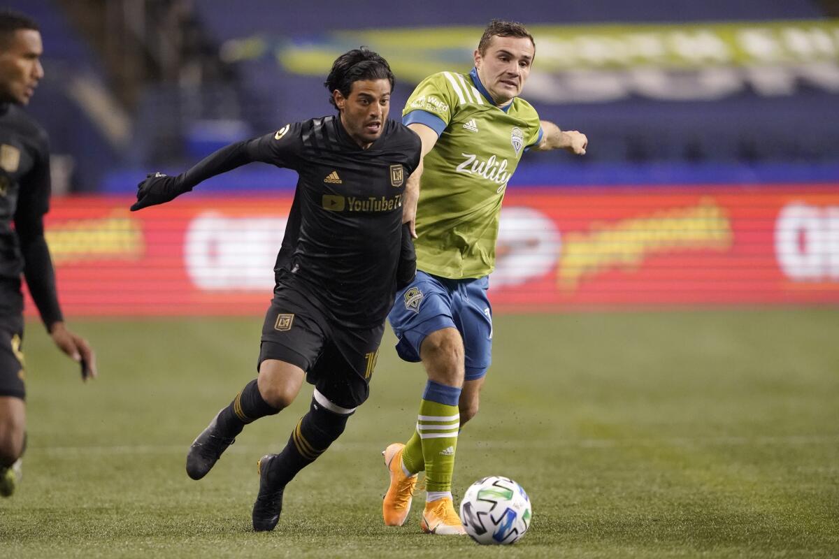 Seattle Sounders forward Jordan Morris and LAFC forward Carlos Vela vie for the ball on the field.