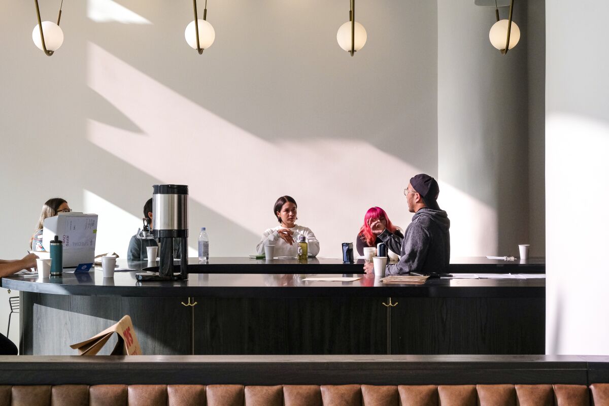 A photo of a few people seated at a minimalist coffee bar