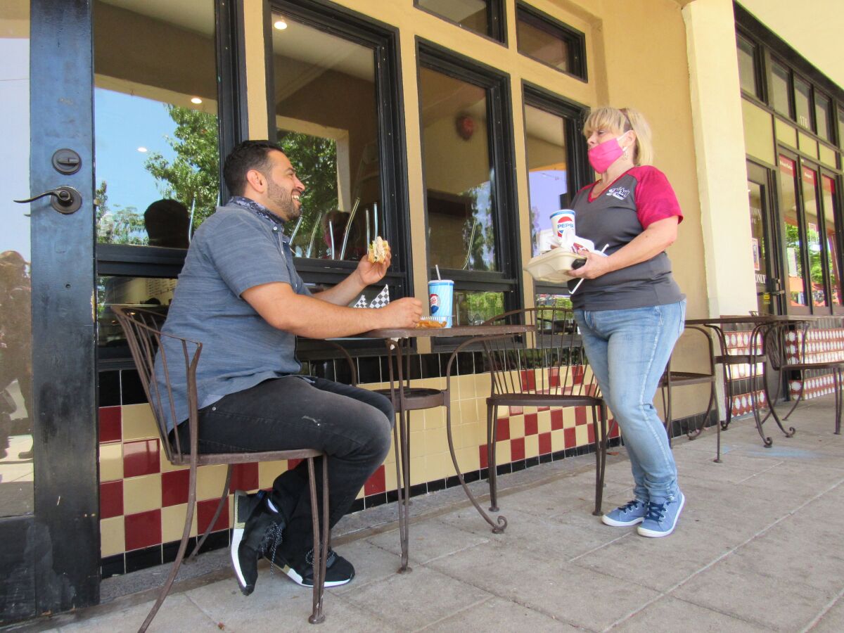 Shauhin Salehyan enjoys a sandwich outdoors with Main Street Donuts & Deli employee Tammi Harold in El Cajon.
