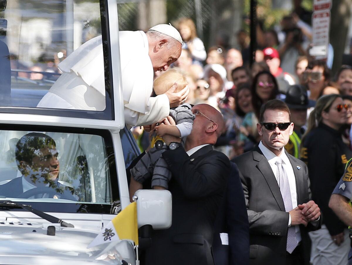 Papa Francisco besa a un bebé durante su recorrida por las calles de Washington en el papamóvil, miércoles 23 de septiembre de 2015.