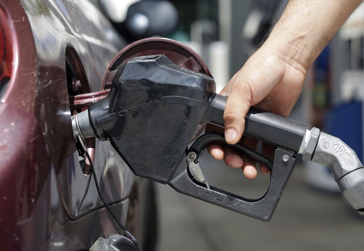 A person's hand holds a gasoline pump while fueling up a vehicle. 