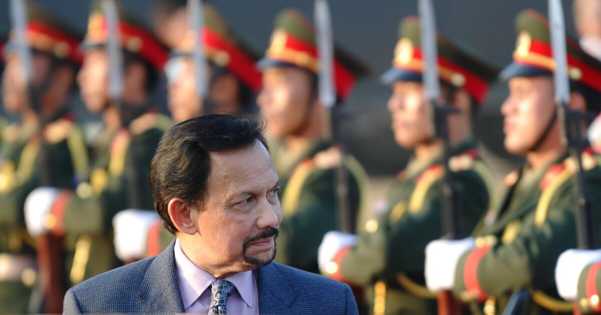 Brunei's Sultan Hassanal Bolkiah walks past an honour guard upon his arrival at Wattay airport to attend the ninth Asia-Europe summit in Vientiane, Laos, on Nov. 4, 2012.