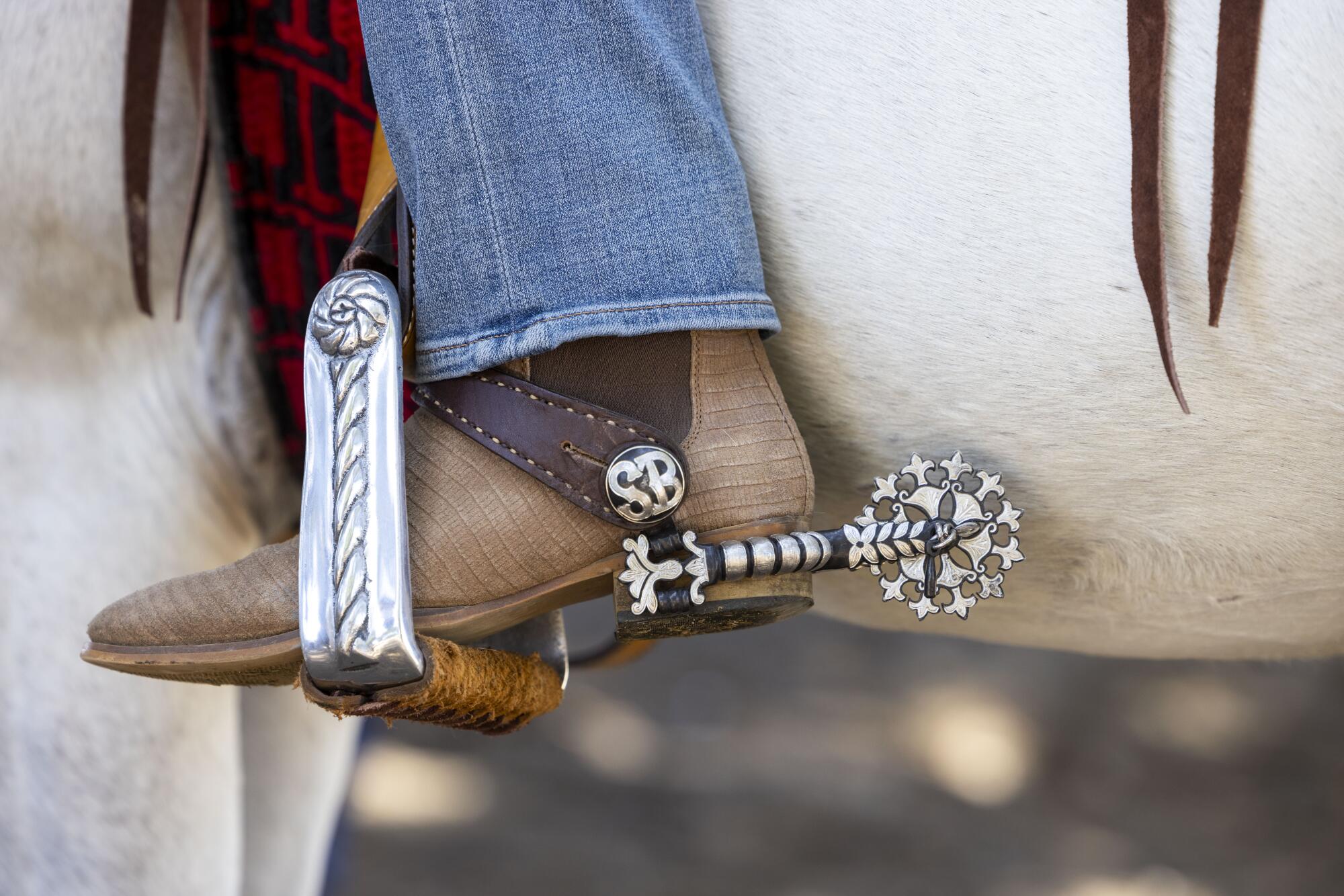 A close-up of a boot and spur of a person riding a horse