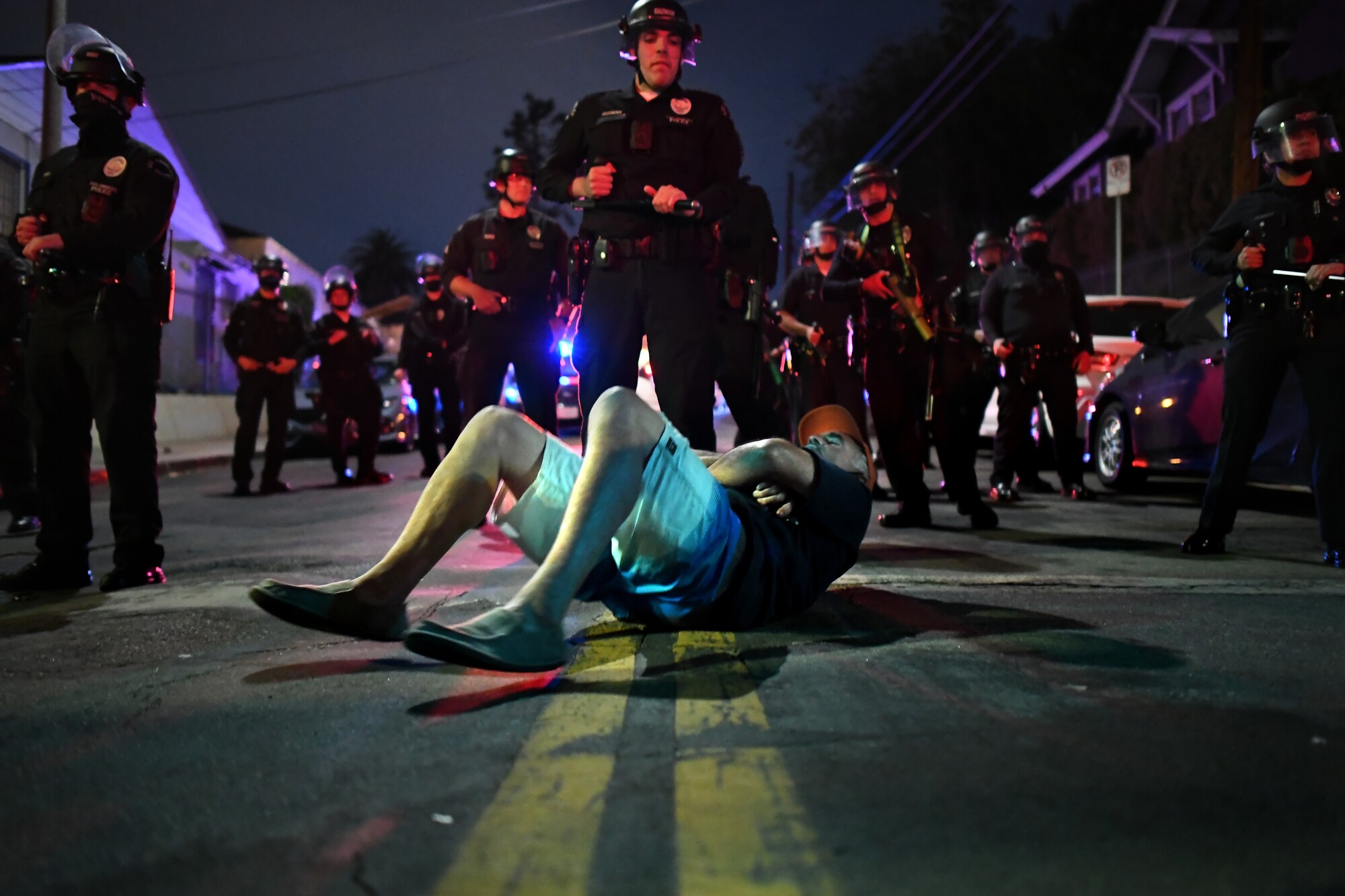 Police stand over a protester lying in the road.