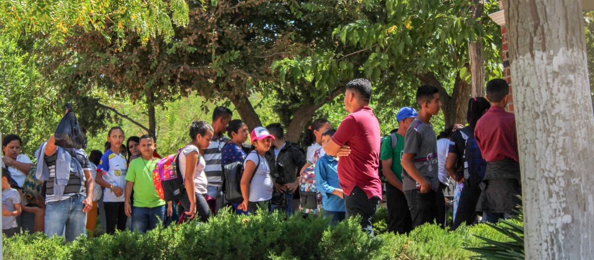 Inmigrantes hondureños esperan en línea afuera de la Casa del Migrante en Juárez, México.