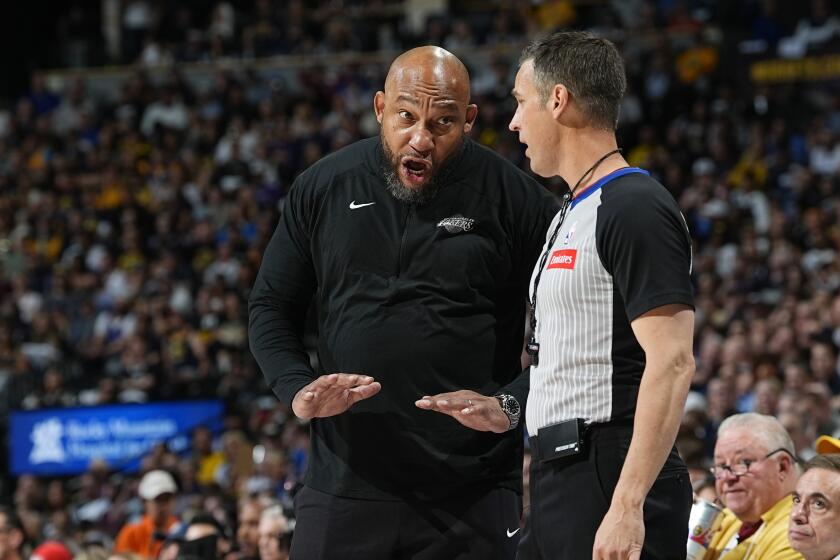 Lakers coach Darvin Ham gestures with his hands while speaking with referee Kevin Scott