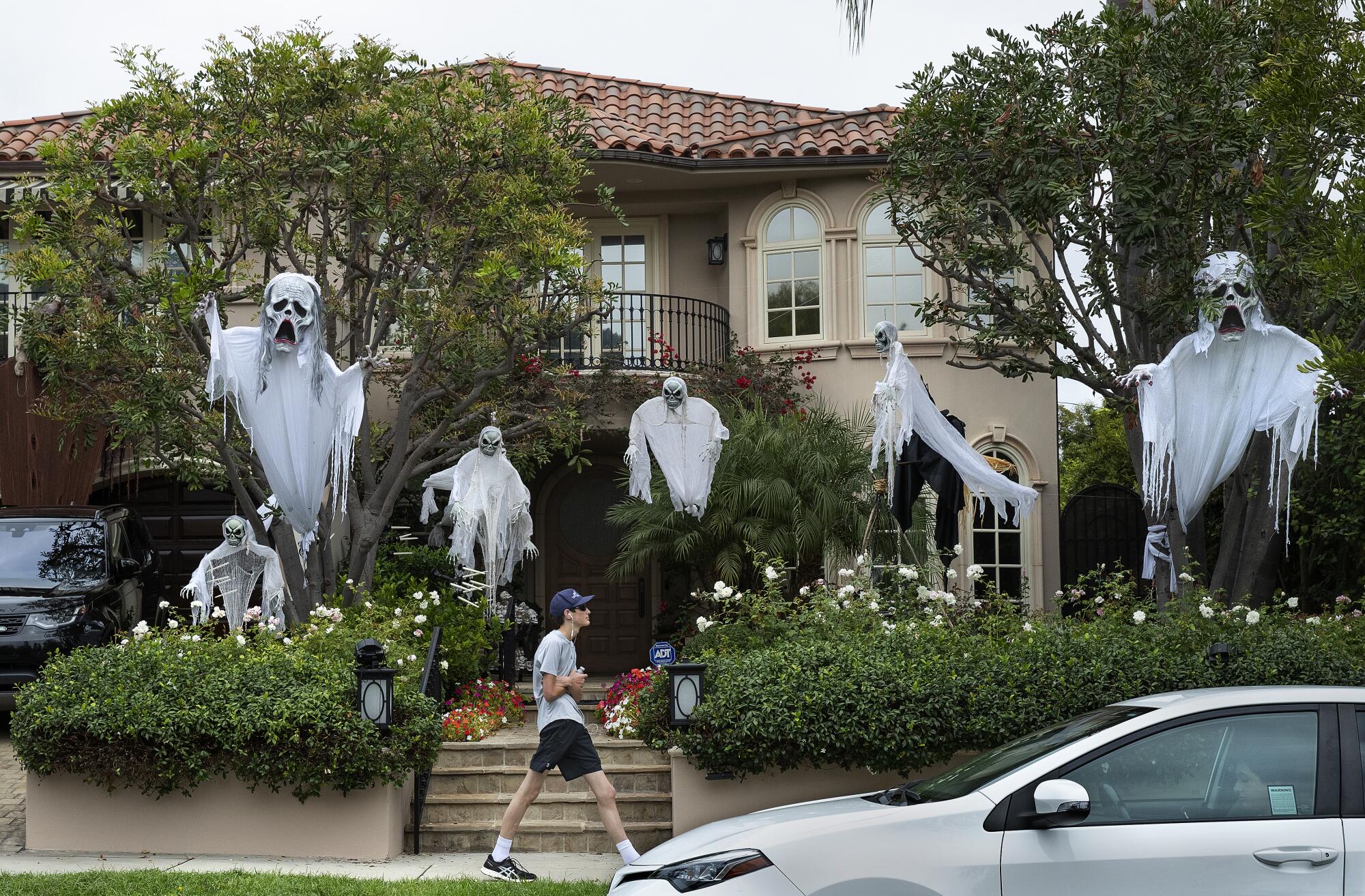 A pedestrian walks past a home with a ghostly entrance on 25th Street in Brentwood.