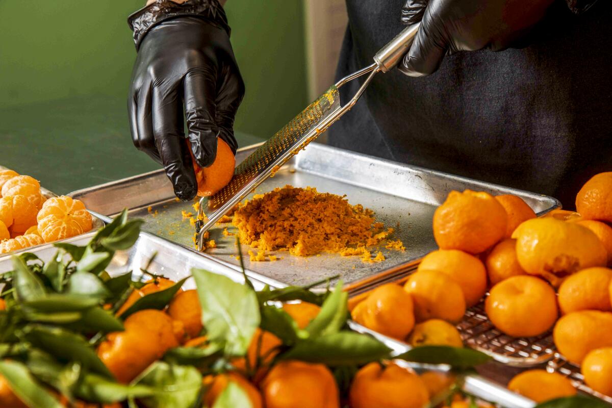 An unseen person's hands zest Kishu mandarins.