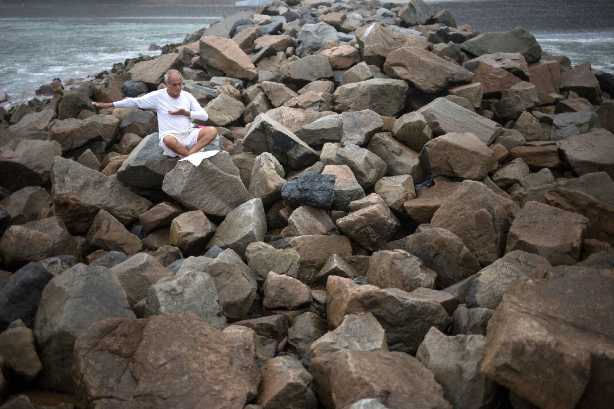 Tomas Cabrera, 86, meditates on a jetty at Agua Dulce beach on March 25, in defiance of government orders to stay away.
