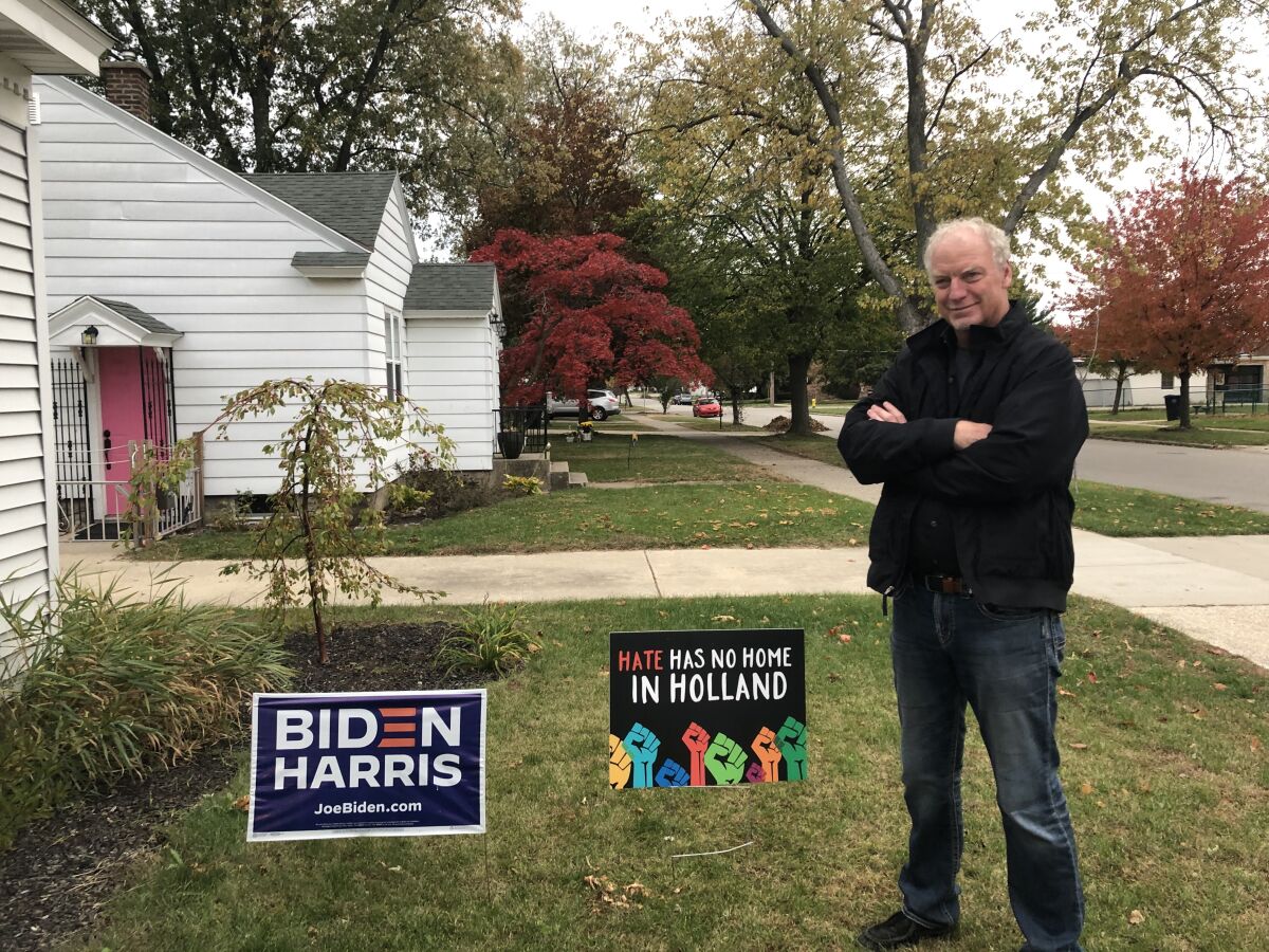 The Rev. Keith Mannes stands next to a Biden-Harris sign in the frontyard of his Holland, Mich., home.