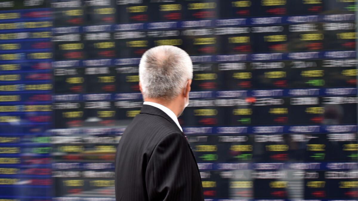 A man walks in front of an electric quotation board displaying the Nikkei key index of the Tokyo Stock Exchange in Tokyo on Nov. 16.