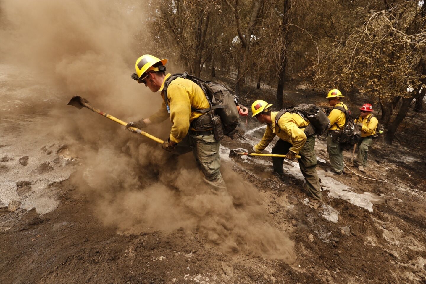 From left, firefighters Aaron Williams, Lyle Bennett Robert Larios and Captain Crawford Gunn, with San Bernardino National Forest put out hot spots Monday morning along State Highway 154 in the Santa Ynez Valley of Santa Barbara County.