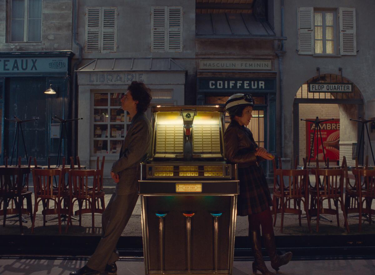 A man and a woman lean against a jukebox in the movie 'The French Dispatch.'