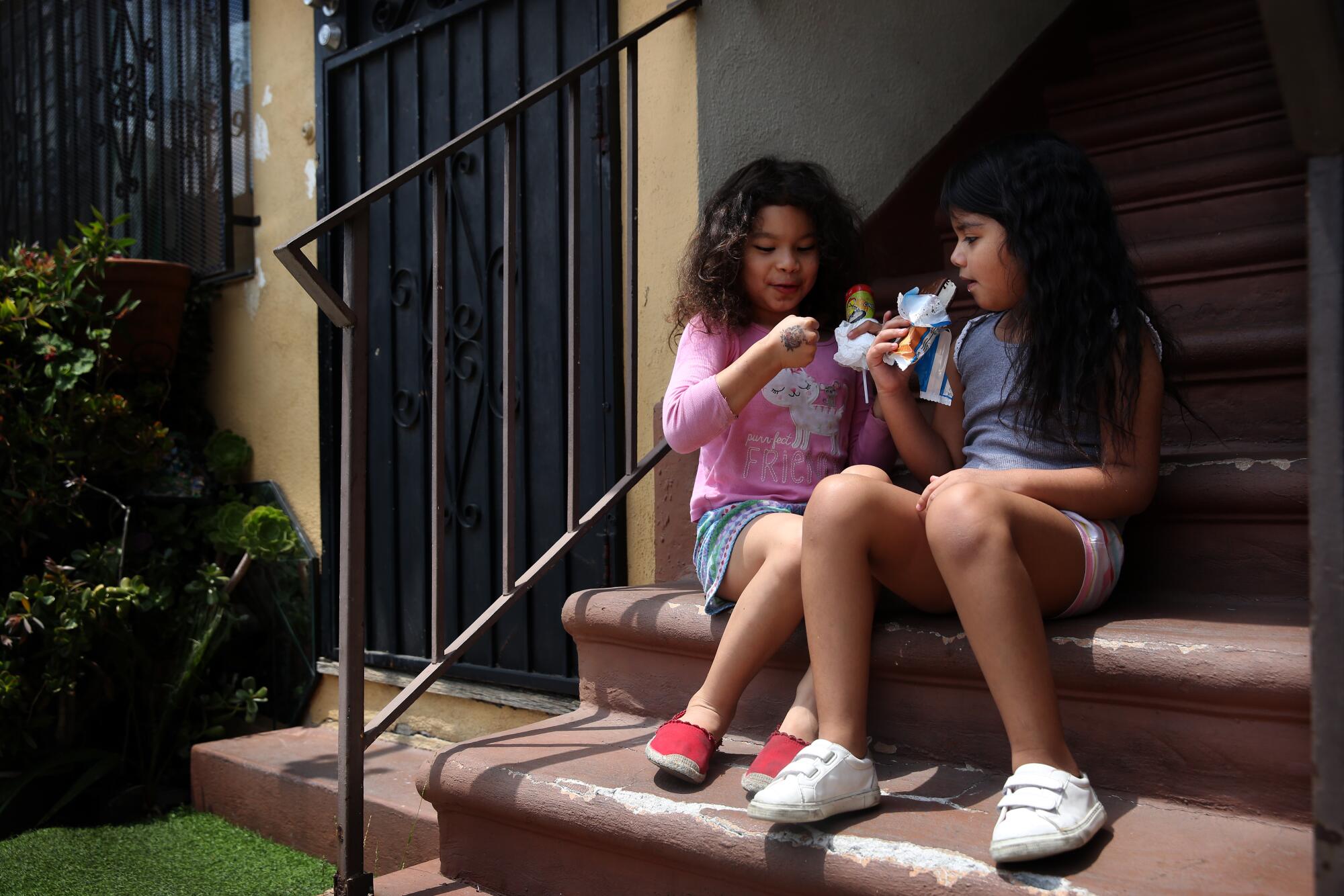 Elizabeth Sanchez, left, 5, and Mia Estrada, 6, eat ice cream at their apartment complex.