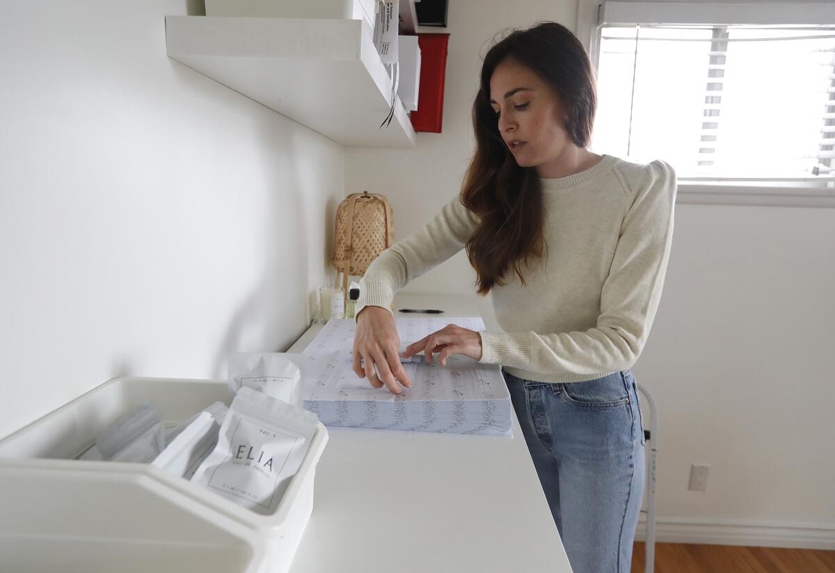 Amanda Meyer wraps a package of her Elia Perfume fragrance line in her home office.