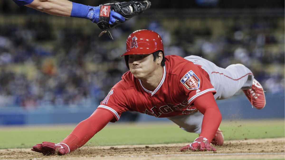 Angels designated hitter Shohei Ohtani dives under the tag of Dodgers first baseman Cody Bellinger on a fourth inning pickoff attempt by pitcher Rich Hill on March 26.
