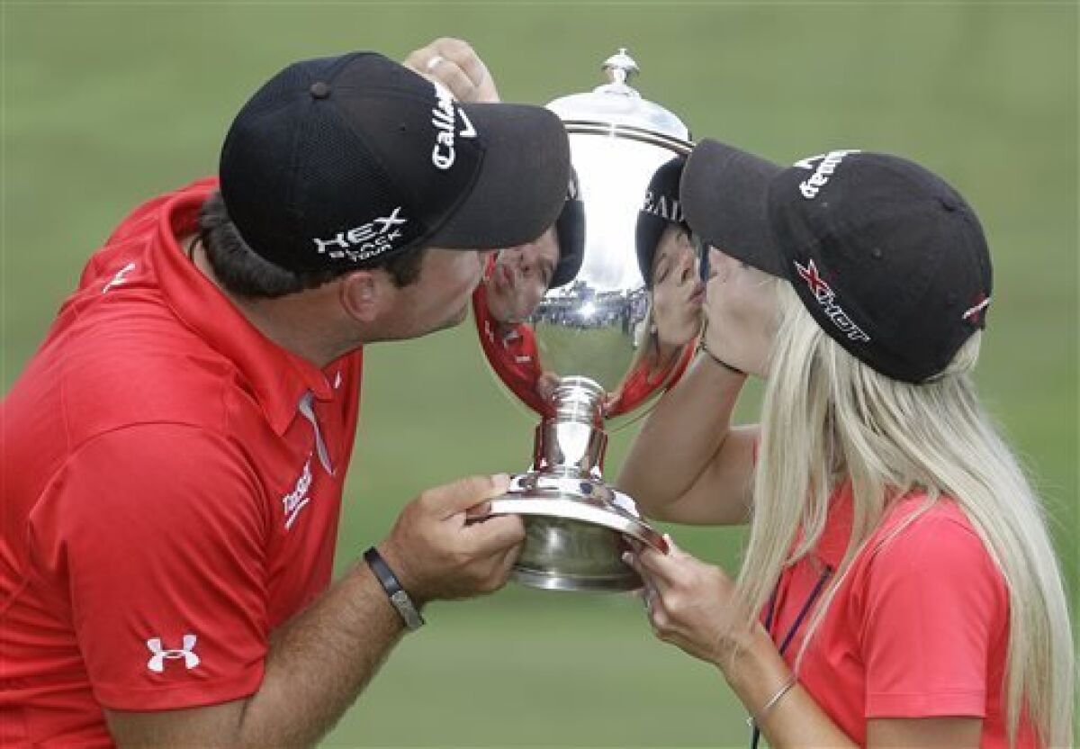 Patrick Reed and his wife and caddy, Justine kiss the Sam Snead trophy after he won the Wyndham Championship golf tournament in a second hole playoff at the Sedgefield Country Club in Greensboro, N.C., Sunday, Aug. 18, 2013. (AP Photo/Bob Leverone)