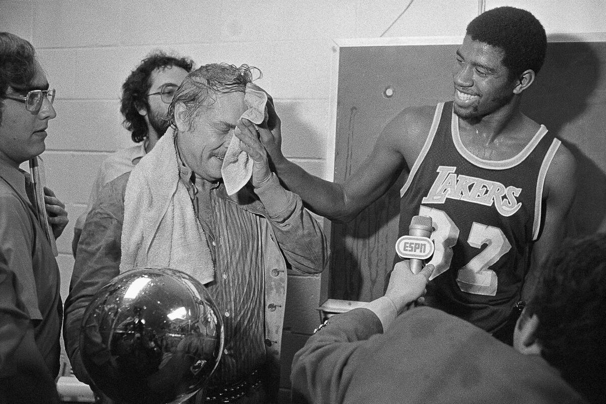 Magic Johnson wipes the face of Lakers owner Jerry Buss after he poured champagne on him following the Lakers' 1980 NBA championship victory over the 76ers.