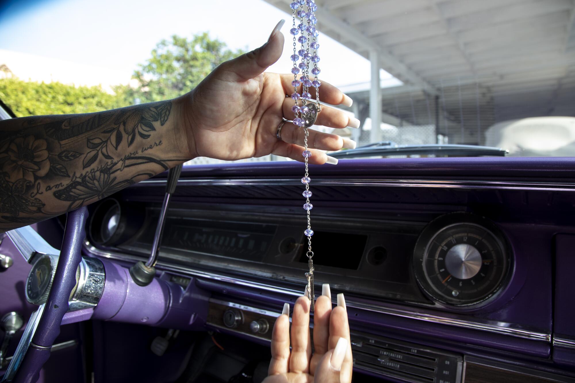 Sofia Toral, 40, shows a purple rosary given to her by her stepmother that matches the color of her 1965 Impala.