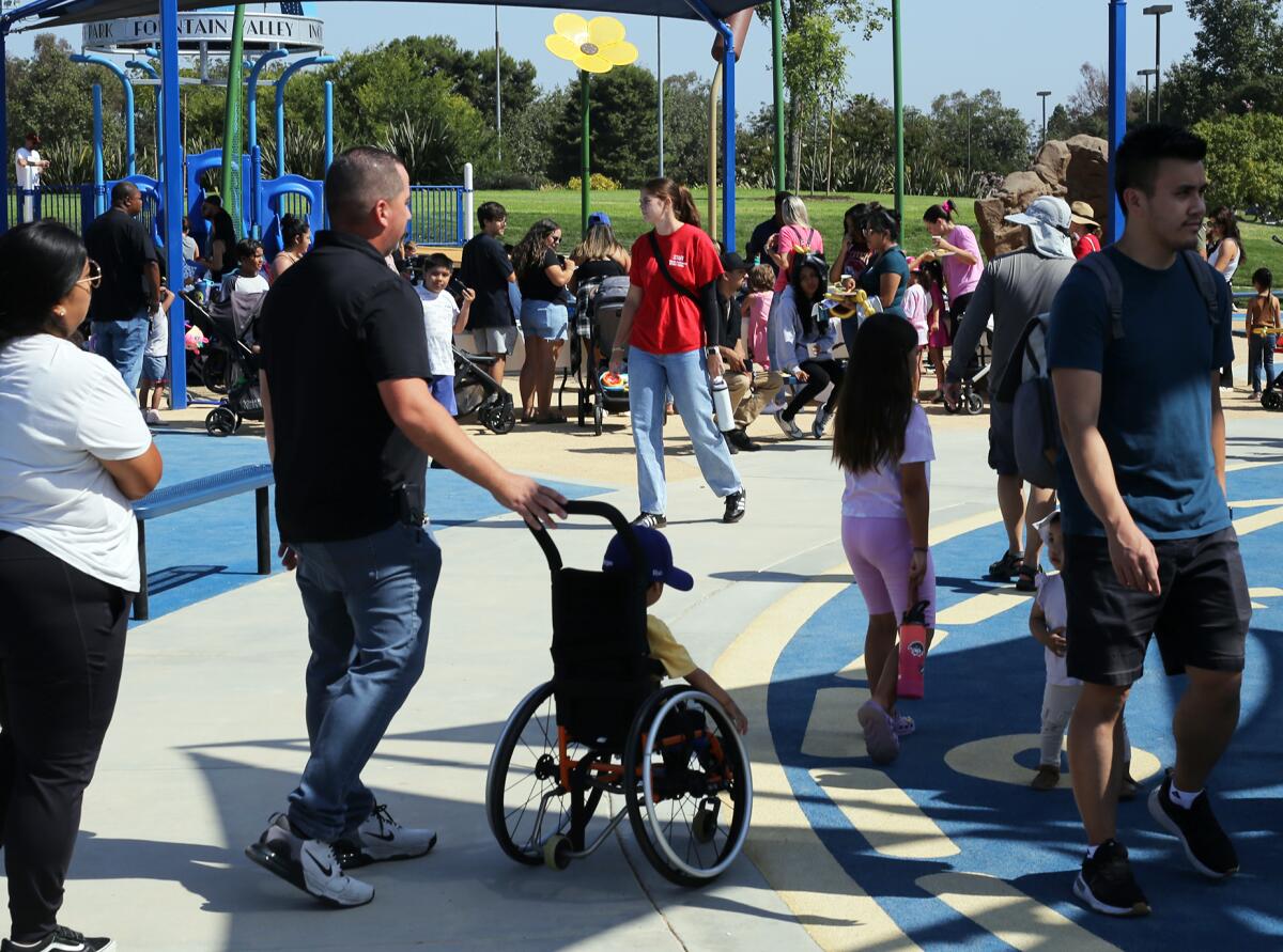 Families with their children experience parallel play at the universally accessible playground in Fountain Valley.