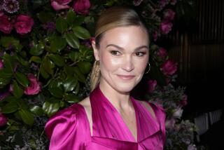 Julia Stiles in pink blouse and hoop earrings at the Christian Siriano Fall/Winter 2023 fashion show in New York
