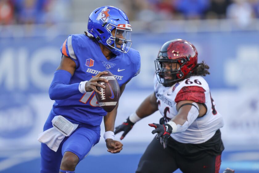 Boise State quarterback Taylen Green (10) is chased out of the pocket by San Diego State defensive lineman Jonah Tavai (66) during the first half of an NCAA college football game Friday, Sept. 30, 2022, in Boise, Idaho. (AP Photo/Steve Conner)