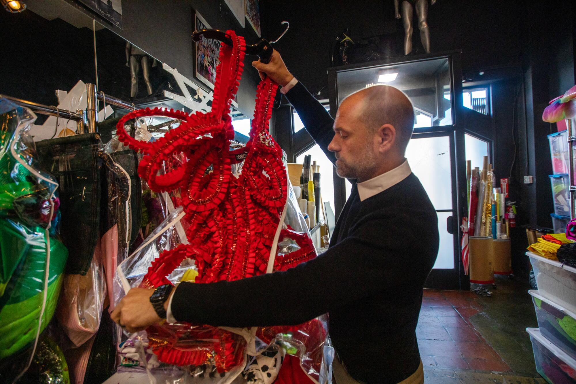 A man holds up a red costume.