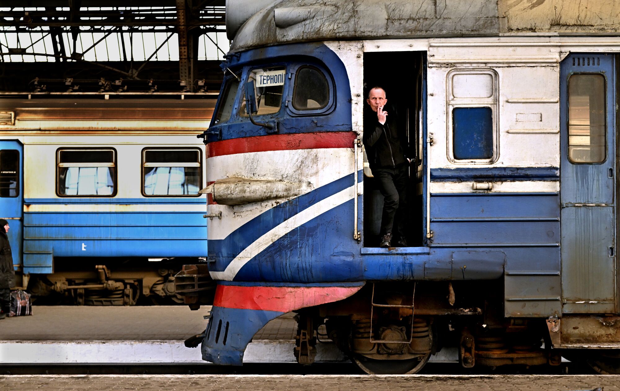A train engineer takes a cigarette break in between before transporting people at the main station in Lviv, Ukraine.