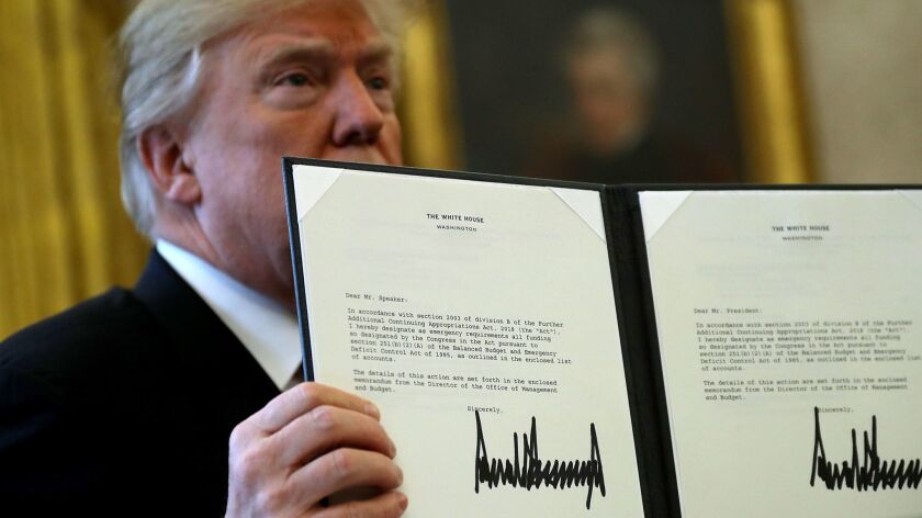 President Trump in the Oval Office holds up a copy of the tax reform bill he signed on Dec. 22, 2017. The tax bill is driving the federal debt to unprecedented levels, the Congressional Budget Office reported Tuesday.