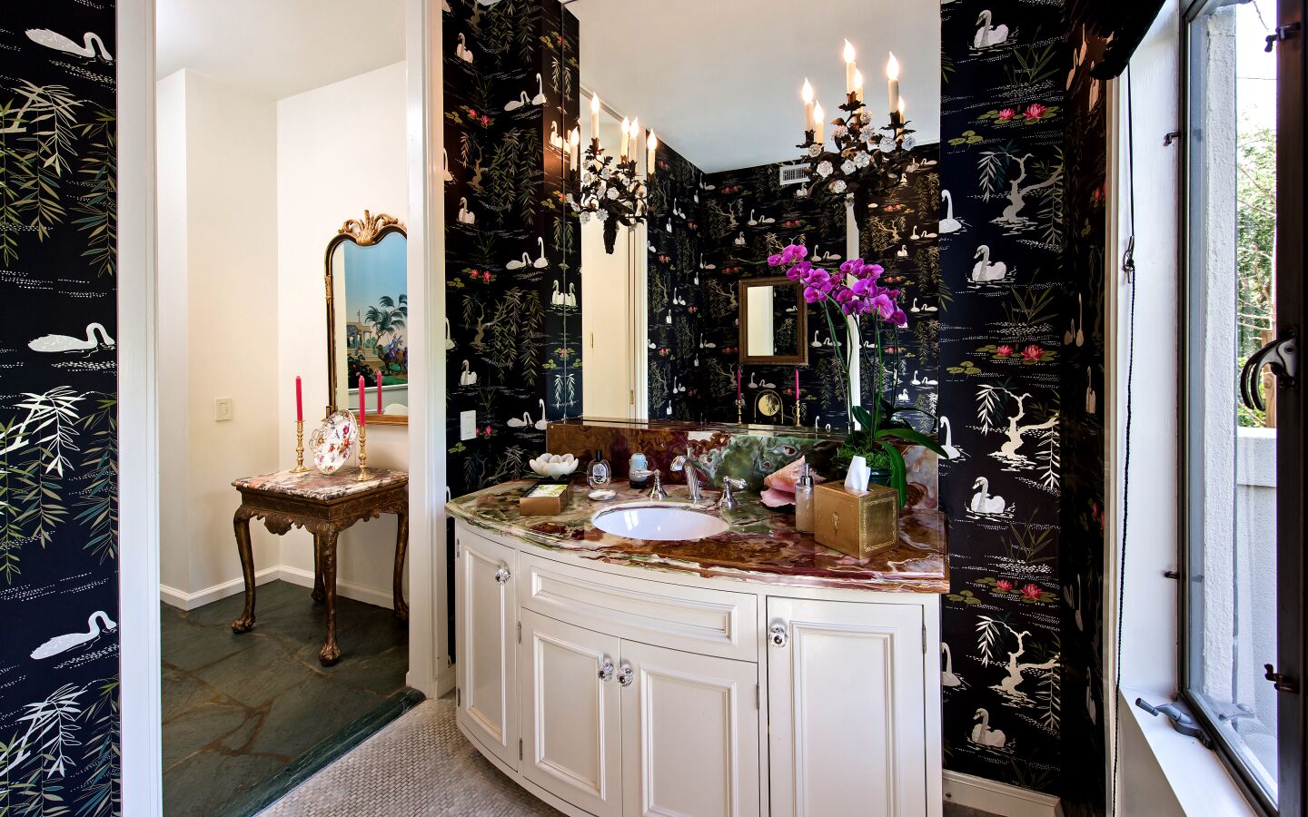 A bathroom inside the home with black wallpaper featuring a design with swans