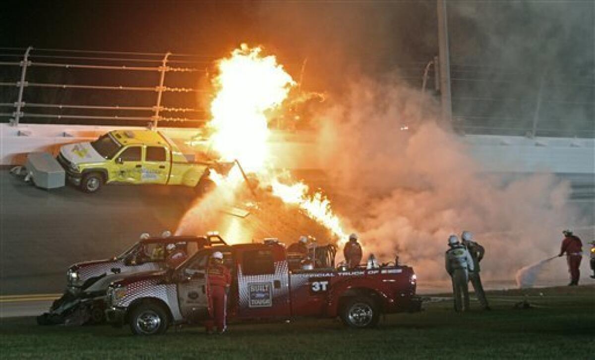 Emergency workers try to put out a fire after Juan Pablo Montoya's car struck the truck during the NASCAR Daytona 500 auto race at Daytona International Speedway in Daytona Beach, Fla., Monday, Feb. 27, 2012. (AP Photo/Bill Friel)