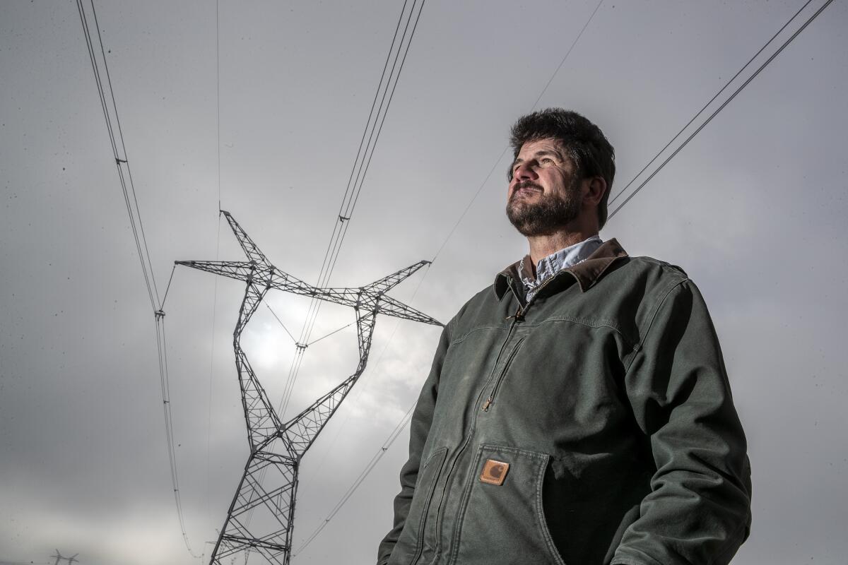 Erik Molvar stands under power lines near a Wyoming ranch, where TransWest Express will connect to a giant wind farm.