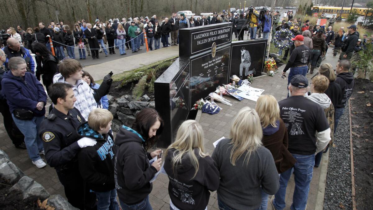 Mourners walk past a memorial for the four slain Lakewood officers at a ceremony marking the first anniversary of their deaths.