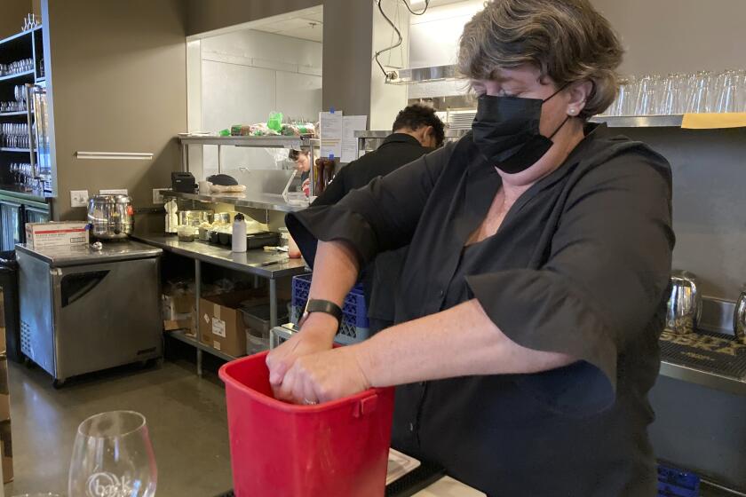 Folsom Vice Mayor Sarah Aquino wrings out a rag before cleaning a table at Back Bistro in Folsom, Calif., on Tuesday, Nov. 23, 2021. Aquino is an insurance broker. But she took a part-time job at one of her favorite local restaurants because they were struggling to hire people. Employers have reported a shortage of workers to meet demand as more people return to normal habits following the disruption of the coronavirus pandemic. Aquino sees it as her civic duty to help out local businesses. (AP Photo/Adam Beam)