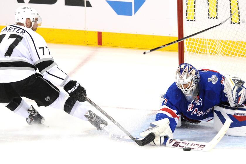 New York Rangers goalie Henrik Lundqvist makes a save on a shot by Jeff Carter as a defenseman's stick goes flying above him during the second period of Game 4 of the Stanley Cup Final.