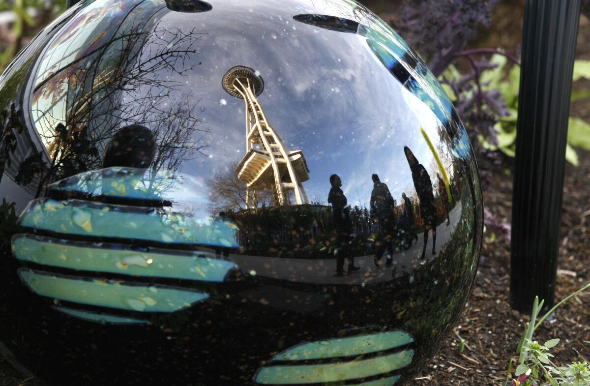 JANUARY 16, 2015. SEATTLE, WA. A glass ball at the Chihuly Garden and Glass museum reflects visitors and the neighboring Space Needle tower in Seattle, WA. (Don Bartletti / Los Angeles Times)