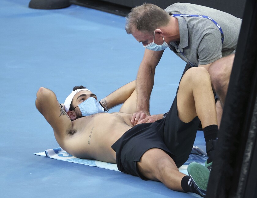 Italy's Matteo Berrettini, left, receives medical treatment during a break while playing Russia's Karen Khachanov during their third round match at the Australian Open tennis championships in Melbourne, Australia, Saturday, Feb. 13, 2021. (AP Photo/Hamish Blair)