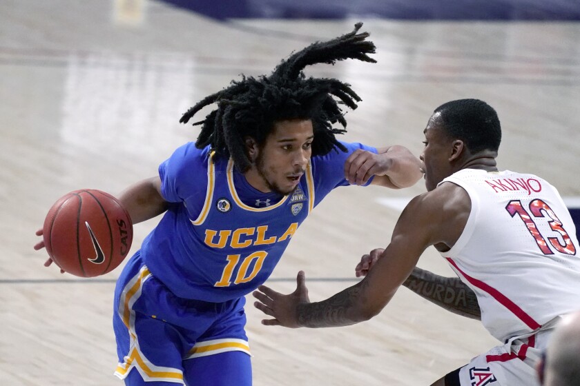 UCLA guard Tyger Campbell drives on Arizona guard James Akinjo during the second half of a Bruins victory on Jan. 9.