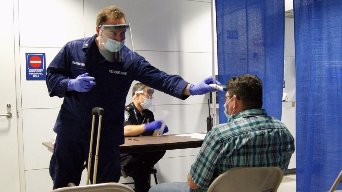 During an Ebola outbreak in 2014, U.S. Coast Guard Health Technician Nathan Wallenmeyer, left, and CBP supervisor Sam Ko screened a passenger, right, who arrived from Sierra Leone, at O'Hare International Airport in Chicago.